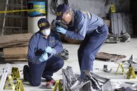 Mayday - Alarm im Cockpit – An Investigator holds up a piece of debris while another Investigator photographs and documents the debris as evidence