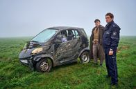 Mord mit Aussicht – Schäfer Georg Kappes (Thomas Krutmann, l.) hat an der Grenze zwischen Nordrhein-Westfalen und Rheinland-Pfalz einen Autounfall beobachtet. Heino (Sebastian Schwarz, r.) überlegt, wie er den Papierkram umgehen kann.