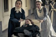 Charité – Ida Lenze (Alicia von Rittberg, M.) wird mit Verdacht auf Blinddarmentzündung in die Charité eingeliefert. Schwester Therese (Klara Deutschmann, l.) und Wärterin Edith (Tanja Schleiff, r.) verlieren keine Zeit.