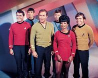 Raumschiff Enterprise – Chefingenieur Scotty (James Doohan, l.), Wissenschaftsoffizier Mr. Spock (Leonard Nimoy, 2.v.l.), Captain Kirk (William Shatner, 3.v.l.), Dr. McCoy (DeForest Kelley, 3.v.r.), Lieutenant Uhura (Nichelle Nichols, 2.v.r.) und Navigator Chekov (Walter Koenig) arbeiten an Bord von Raumschiff Enterprise.