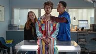 Extraordinary – Als Jen (Máiréad Tyers, l.) und Jizzlord (Luke Rollason, M.) den Tierarzt (John Macmillan, r.) aufsuchen, macht dieser bei der Untersuchung eine Entdeckung, die Hinweise auf Jizzlords geheimnisvolles früheres Leben geben könnte.