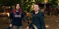 Silverpoint – Kaz (Maiya Silveston, l.) und Bea (Aoife Hughes, r.) sind zurück im Camp und beobachten den Dinosaurier. Sie versuchen, alle vor dem T-Rex in Sicherheit zu bringen.