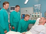 In aller Freundschaft – Achim (Johannes Steck, rechts) hat es auch ohne Medikament geschafft den Virus zu besiegen. Sebastian (Steve Wrzesniowski, 3. von links), Roland (Thomas Rühmann, 2. von links) und Martin (Bernhard Bettermann) sind erleichtert, dass es Achim besser geht. Jetzt steht Sebastians Geburtstagsparty nichts mehr im Weg.