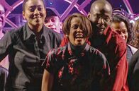 Whitney - Can I Be Me – Whitney Houston (Mi.) freut sich mit ihrem damaligen Partner Bobby Brown (3.v.r.) und der Crew über ein gelungenes Konzert.