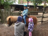 Ich bin Ich – Gleicht geht es los. Jakob sitzt aufgeregt auf seinem Pony und darf gleich losreiten. Seine vierjährige Schwester Eva (re.) und sein Reitlehrer (li.) begleiten ihn.