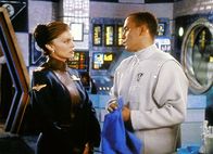 Babylon 5 – Dr. Franklin (Richard Biggs, re.) hat Captain Lochley (Tracy Scoggins) ins Medlab gebeten, um ihr den Befund der Autopsie mitzuteilen.