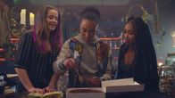 Spellbound – Verzaubert in Paris – Amy (Imogen Mackie Walker, l.) und Lola (Gomolemo Kitso Tsagae, r.), die beide ihre Fähigkeiten zu zaubern verloren haben, sind auf Ceces (Hailey Romain, M.) Hilfe angewiesen und bringen ihr bei, einen Schokoladenkuchen zu verhexen.