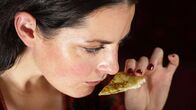 Puls – Puls Orthorexie – Wenn gesund essen zum ungesunden Zwang wird Eine junge Frau schnuppert kritisch an einem Stück Essen. Copyright: SRF