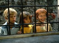 Astrid Lindgren:: Pippi in Taka-Tuka-Land – Erstaunt sehen Pippi (Inger Nilsson, r.), Tommy (Pär Sundberg, l.) und Annika (Maria Persson, M.) dem Treiben der Seeräuber in einer Taverne zu.