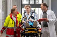 In aller Freundschaft – Die Notärztin (Anne Richter, li.) übergibt Laurenz Beninger (Hannes Linder, mi.) in der Sachsenklinik an Dr. Hoffmann (Julian Weigend, re.). Laurenz hat Epilepsie und genau dafür seinen Hund Balu, der ihn warnen soll, bevor er einen Anfall bekommt. Doch das hat dieses Mal nicht funktioniert.