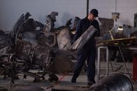 Mayday - Alarm im Cockpit – REENACTMENT - In the investigative hangar, an on-site assistant examines a piece of debris from the wreckage of Fly Dubai Flight 981. (Cineflix 2021/Darren Goldstein)