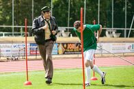 Hubert und Staller – Staller (Helmfried von Lüttichau, links) befragt Stefan Schneider (Urs Fabian Winiger), wann er Andreas Sonnleitner das letzte Mal gesehen hat. Dabei muss er neben dem Fußballer herlaufen, der gerade mit einem Schlitten Krafttraining macht.