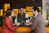 Die Rosenheim-Cops – Beim Abendessen im "Times Square" erfährt Kommissarin Andresen (Sophie Melbinger, l.) im Beisein von Jo (Christian K. Schaeffer, M.), weshalb Controller Donato (Paul Brusa, r.) seine Teilnahme am Fachvortrag abgesagt hat.