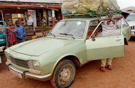 Wilde Wege – Moustapha Sow (re.) mit seinem Taxi, einem über 40 Jahre alten Peugeot 504