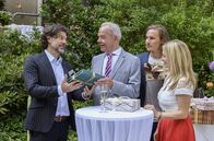 Sturm der Liebe – Sandra (Sarah Stork, r.), William (Alexander Milz, 2.v.r.) und Alexander (Gregory B. Waldis, l.) überreichen Werner ein ganz besonderes Geburtstagsgeschenk.