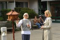 SOKO Stuttgart – Im Hof des Seniorenheims spricht Martina Seiffert (Astrid M. Fünderich, r.) mit Ursel Vogt (Katharina Matz, l.) über das Opfer, während im Hintergrund Senioren (Komparsen, M.) die Sonne genießen. Den Aussagen zufolge war das Opfer an der ehemaligen Schulleiterin interessiert.