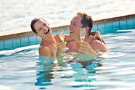 All Inclusive - Willkommen im Paradies – Ausgelassen trinken Lucy (Kristin Davis, l.) und Joey (Jon Favreau, r.) Sekt in einem Pool. Die Paartherapie scheint bei beiden Wunder zu wirken, denn sie finden immer mehr zueinander.
