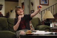 Two and a Half Men – Ein Mädchen hat Jake (Angus T. Jones) eine Halskette geschenkt. Er schickt ihr ein Foto als Beweis, dass er den Schmuck auch wirklich trägt.