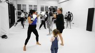 Puls – Hochschwangere Frau im Boxtraining mit anderen Frauen und Männern und einem Kind, das zuschaut