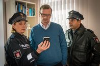 Notruf Hafenkante – Claudia (Janette Rauch, l.) und Tarik (Serhat Cokgezen, r.) zeigen Dr. Mertin (Jörg Bundschuh, M.) ein Foto des Medikaments, das sie bei seiner Patientin gefunden haben. Dr. Mertin behauptet, dass sie dieses Medikament nicht von ihm verschrieben bekommen habe.