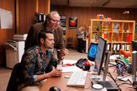 Browser Ballett – Der neue KI-Kollege nimmt Ben (Nicolas F. Türksever, vorne), Volker (Rainer Reiners, hinten) und den anderen Kolleg en und Kolleginnen im Handumdrehen jede Menge Arbeit ab. Weniger Arbeit? Klingt super! Doch die Fähigkeiten der KI sind irgendwie auch beängstigend.
