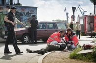 Notruf Hafenkante – Melanie (Sanna Englund, l.) und Mattes (Matthias Schloo, 2.v.l.) ermitteln im Falle einer Fahrerflucht, während Notarzt Haase (Fabian Harloff, r.) und ein Kollege (Komparse) den verletzten Beifahrer (Bert Tischendorf, liegend) versorgen.
