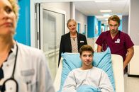 Bettys Diagnose – Lukas Hilpert (Niklas Lö?ffler, r.), Dr. Helena von Arnstett (Claudia Hiersche, l.) und Mechthild Puhl (Sybille J. Schedwill, 2.v.l.) fahren den gut gelaunten Patienten Tano Elf (Jascha Rust, M.) mit seinem Krankenbett zur Untersuchung.