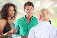 Death in Paradise – Lauren Campese (Vinette Robinson, l.) und Marc Campese (Tristan Gemmill, M.) genießen noch die Feier bei Leo Pascal (Adrian Scarborough, r.). Doch schon bald gerät Lauren ins Visier der Polizei. Sie kannte das Opfer besser, als sie zugeben möchte.