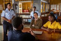 Death in Paradise – Henry Baptiste (Solomon Israel, 2. v. l.) gerät unter Mordverdacht und wird auf dem Polizeirevier vor Marlon Pryce (Tahj Miles, l.), Darlene Curtis (Ginny Holder, M.), Detective Neville Parker (Ralf Little, 2. v. r.) und Naomi Thomas (Shantol Jackson, r.) befragt.