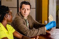 Death in Paradise – Im Polizeirevier untersuchen Naomi Thomas (Shantol Jackson, l.) und Detective Neville Parker (Ralf Little, r.) akribisch einen Zettel mit einem Hilferuf und führen entsprechende Nachforschungen durch.