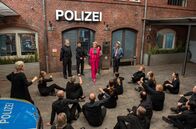 Großstadtrevier – Ein Machtwort von Revierleiterin Frau Küppers (Saskia Fischer, h.M.) beendet den Sitzstreik des Chors (NDR Vokalensemble, v.) vor der Wache (mit Torsten Münchow, h.l., Sven Fricke, h.2.v.l., Maria Ketikidou, h.2.v.r. und Enrique Fiß, h.r.).; ARD GROSSSTADTREVIER XXXVII. STAFFEL, FOLGE 500, "Vendetta" Uhr im ERSTEN. Ein Machtwort von Revierleiterin Frau Küppers (Saskia Fischer, h.M.) beendet den Sitzstreik des Chors (NDR Vokalensemble, v.) vor der Wache (mit Torsten Münchow, h.l., Sven Fricke, h.2.v.l., Maria Ketikidou, h.2.v.r. und Enrique Fiß, h.r.).