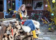 Rabe Rudi - Vorlese-Geschichten – Milena Tscharntke und Rabe Rudi. Milena liest aus dem Buch vor, das sie in der Hand hält. Rudi schaut sie an und hört zu.