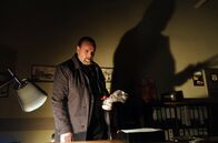 Polizeiruf 110 – Lemp (Felix Vörtler) holt eine Flasche Schnaps aus der Schublade.