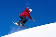 Snowboard: Weltcup – Snowboarder jumping through air with deep blue sky in background