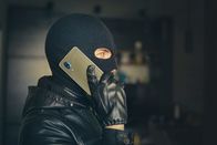 Reingelegt! – Young adult in black clothes with hidden face. Ill-intended fraudster uses mobile. Fraudster calls. Mobile racket. Hacker hijacks by phone. Cellphone account fraud. Scam