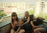 Kokon – Nora (Lena Urzendowsky, l.), Jule (Lena Klenke, M.) und Aylin (Elina Vildanova, r.) chillen auf dem Balkon ihres Plattenbaus von dem man eine weiten Blick über Berlin hat.