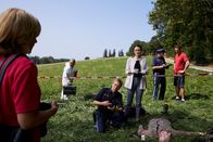 Die Rosenheim-Cops – Polizeihauptmeister Mohr (Max Müller, M.) und Pathologin Mai (Sina Wilke, r.) schildern Kommissarin Danner (Katharina Abt, l.) den vermeintlichen Tathergang. (Im Hintergrund: Komparsen).