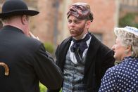 Father Brown – Sid Carter (Alex Price, M.) erlaubt sich einen Spaß mit Mrs McCarthy (Sorcha Cusack, r.) und Father Brown (Mark Williams, l.) am Filmset. Er bedient sich unbemerkt an den Requisiten der Filmcrew.