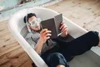 111 – Funny businessman in flippers and mask lies in bathtub and reads a book, humor. Business lottery concept