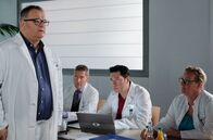 In aller Freundschaft – Hans-Peter Brenner (Michael Trischan, li.) bespricht in der morgendlichen Ärztekonferenz den Fall seiner Mutter, die an Krebs leidet. Da es ihr nach der Entfernung des Primärtumors schnell wieder besser ging, will Brenner nun zügig mit der Chemo anfangen, um die Metastasen zu bekämpfen. Während Hans-Peter an Heilung glaubt, sind seine Kollegen der Meinung, dass man Luise Brenner nur noch palliativ behandeln sollte ... es sind einfach zu viele Metastasen. v.li.: Dr. Rolf Kaminski (Udo Schenk), Dr. Philipp Brentano (Thomas Koch), Ärztin (Komparsin, Elke Kauert)