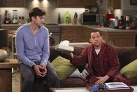 Two and a Half Men – Walden (Ashton Kutcher, l.) bemerkt mitten in der Nacht, dass Alan (Jon Cryer, r.) heulend auf dem Sofa sitzt. Was ist nur der Grund dafür?