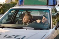 Hubert und Staller – Von links: Hubert (Christian Tramitz) und Staller (Helmfried von Lüttichau) beobachten vom Streifenwagen aus, dass Klaus Böttcher von einem Dach in die Tiefe springen will.