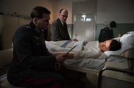 Charité – Prof. Sauerbruch (Ulrich Noethen, M.) am Bett seines Sohnes Peter (Maximilian Klas, r.), der mit Gelbfieber aus Stalingrad in die Charité eingeliefert wurde. Peter bekommt Besuch von einem engen Freund: Claus Schenk Graf von Stauffenberg (Pierre Kiwitt, l.).