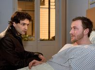 In aller Freundschaft – Als Freddy (Luca Zamperoni, links) seinen Freund Hajo Hausmann (Florian Reiners) in der Sachsenklinik besucht, fragt er ihn immer, ob er weiß, mit wem ihn Stefanie betrogen hat. Doch Hajo blockt ab und rät Freddy, um seine Ehe zu kämpfen.