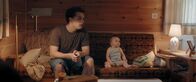 Windstill – Rafael (Anselm Bresgott) und Baby Olivia (Patricia Graf) sitzen auf dem Sofa.