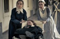 Charité – Ida Lenze (Alicia von Rittberg, M.) wird mit Verdacht auf Blinddarmentzündung in die Charité eingeliefert. Schwester Therese (Klara Deutschmann, l.) und Wärterin Edith (Tanja Schleiff, r.) verlieren keine Zeit.