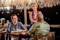 Death in Paradise – Polizeichef Selwyn Patterson (Don Warrington, r.) versucht Detective Neville Parker (Ralf Little, l.) bei einem Glas Rum dazu zu überreden, die Insel nicht zu verlassen, während Catherine Bordey (Elizabeth Bourgine, M.) gelegentlich Rum für sie nachschenkt.