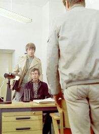 Polizeiruf 110 – hr-fernsehen POLIZEIRUF 110: DER MANN, Kriminalfilm, DDR 1975, Regie: Manfred Moschblech Uhr. Wachmeister Subras (Alfred Rücker, stehend) mit dem Verdächtigen Franz Werker Fred Düren, sitzend)