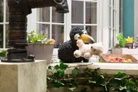 Siebenstein – Rabe Rudi (Werner Knoedgen) sitzt auf dem Brunnenrand und hält seinen Teddy im Schnabel.
