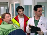In aller Freundschaft – Der Fliesenleger Hans Lambert (Jürgen von der Lippe, links) wird nach einem Unfall vom Notarzt (Roman Petermann, Mitte) in die Sachsenklinik eingeliefert. Als Dr. Brentano (Thomas Koch) die beiden in Empfang nimmt, pfeift Hans Lambert schon wieder hübschen Patientinnen hinterher.